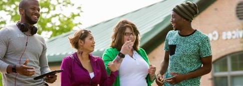 Four students walking outside laughing.